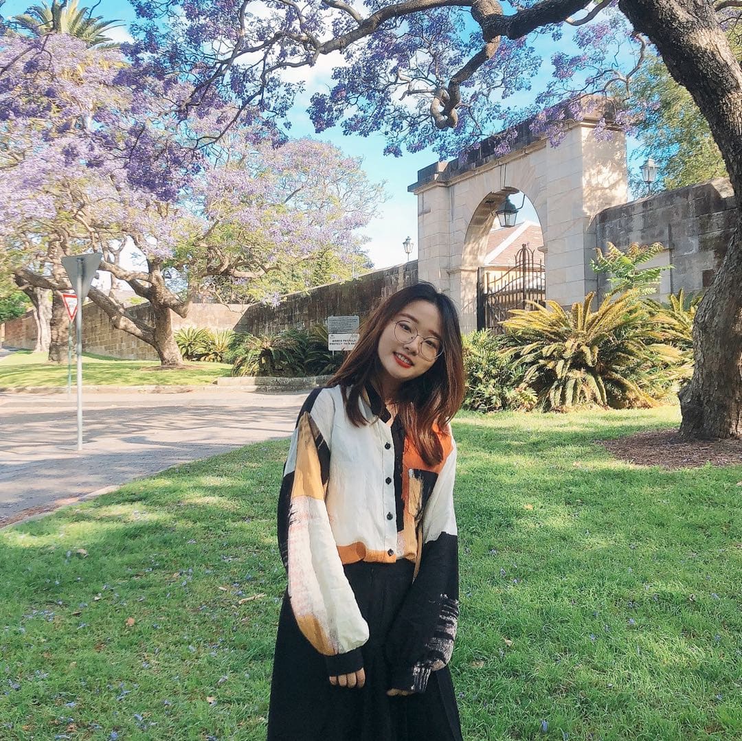 a girl standing below a purple tree