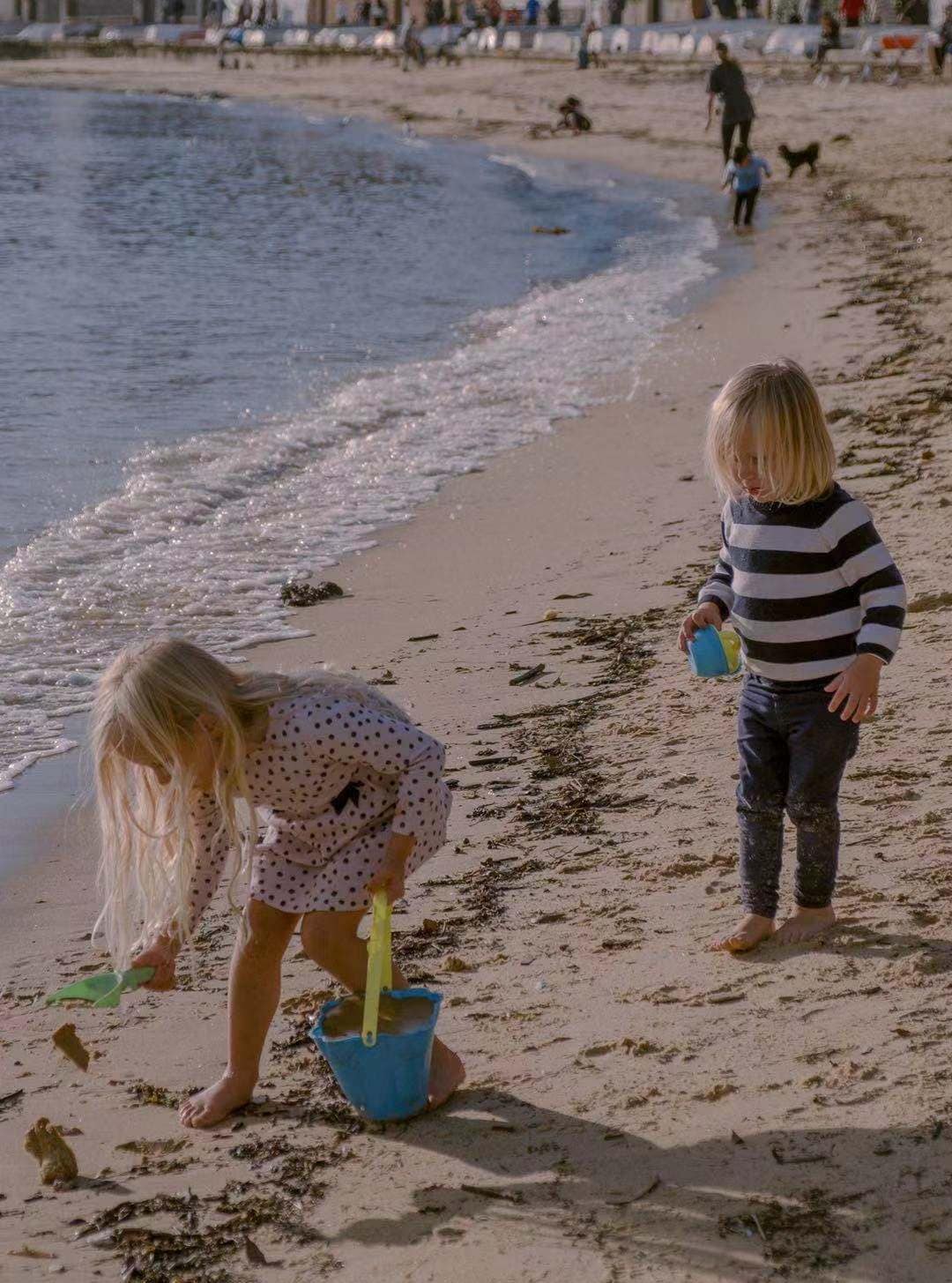 a young boy and a girl playing with sand in a beach