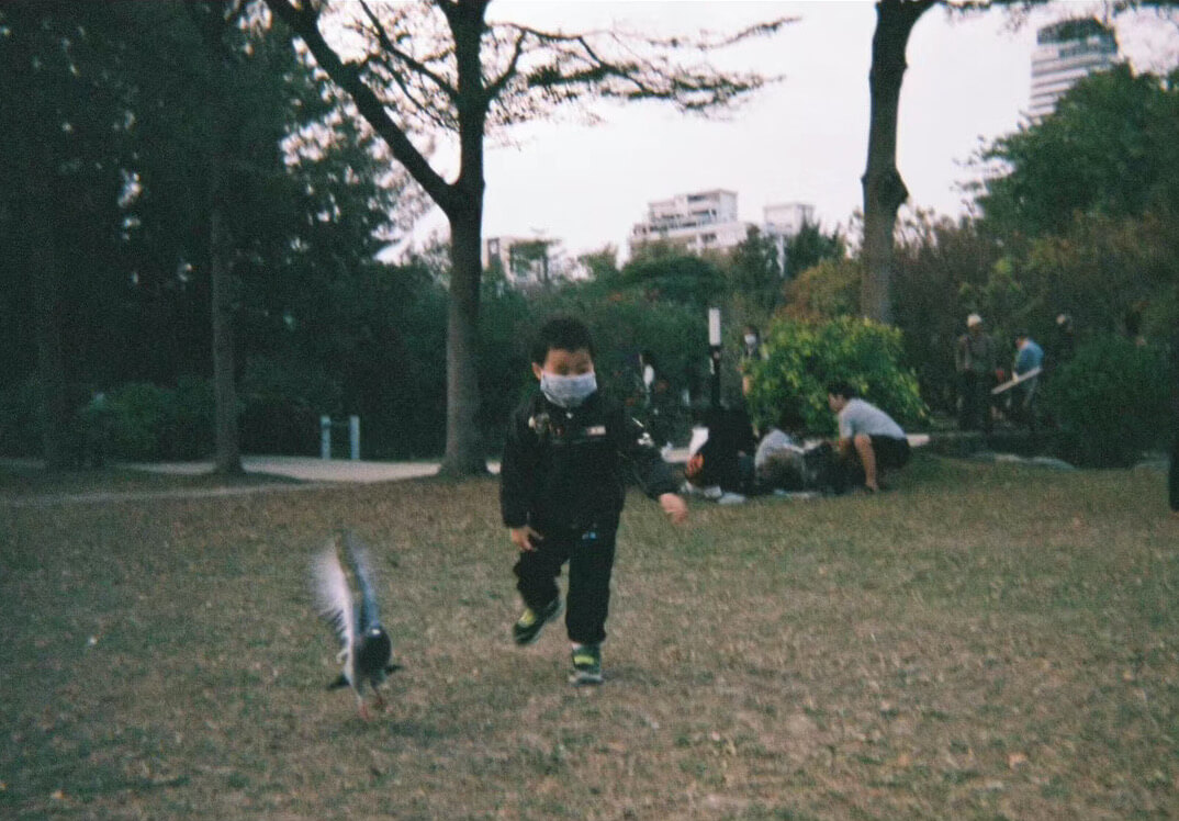 A kid wearing a mask chasing birds